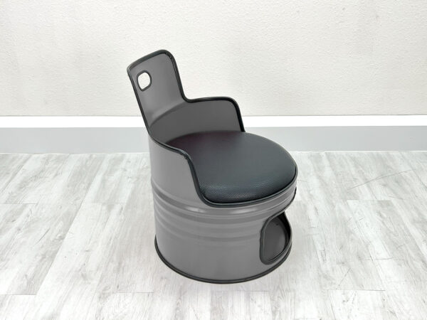 Grauer Ölfass Sessel mit schwarzem Sitzpolster, schwarzem Kantenschutz und Stauraum unter der Sitzfläche vor weißem Hintergrund