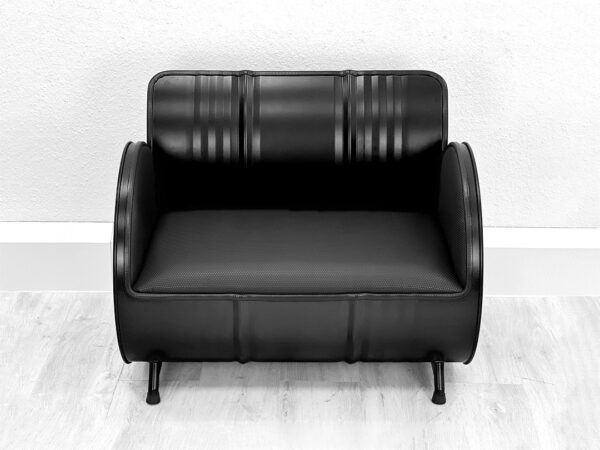 Frontalansicht von schwarzem Ölfass Sofa mit schwarzer Polsterung auf weißem Holzboden vor weißer Wand
