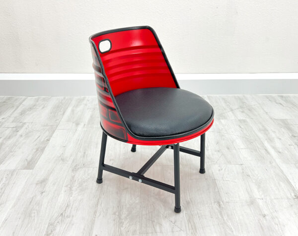 Esszimmer Stuhl aus Ölfass in Grau mit schwarzem Sitzpolster, schwarzen Metallbeinen und schwarzem Kantenschutz auf weißem Holzboden vor weißem Hintergrund