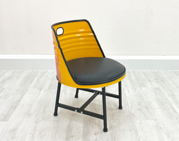Upgecycelter Ölfass Esszimmer Stuhl in Gelb mit schwarzem Sitzpolster, schwarzen Metallbeinen und schwarzem Kantenschutz auf weißem Holzboden vor weißem Hintergrund