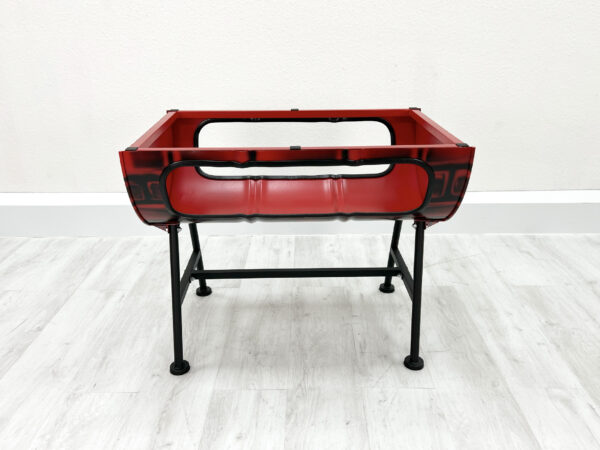 Tischgestell Mick in Rot mit aufgesprayten Backsteinen ohne Tischplatte auf Metallfüßen vor weißer Wand auf weißem Holzboden