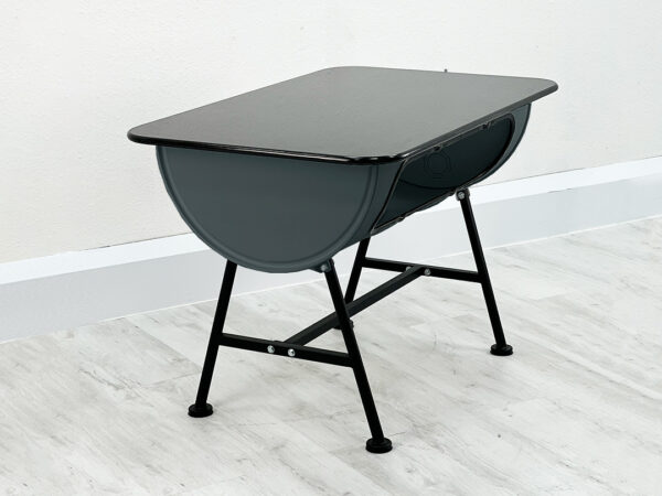 Esstisch Mick aus einem halben grauen Ölfass mit Granit Tischplatte auf schwarzen Beinen vor weißer Wand auf weißem Holzboden