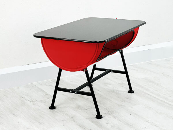 Roter Upcycling Ölfass Tisch mit Stauraum im Inneren und schwarzer Granittischplatte auf Metallfüßen vor weißer Wand auf weißem Holzboden